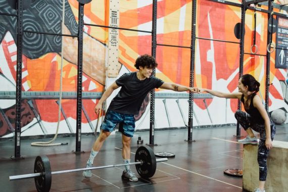 Cheerful gym interaction between a man and woman sharing a fist bump in a vibrant fitness environment.